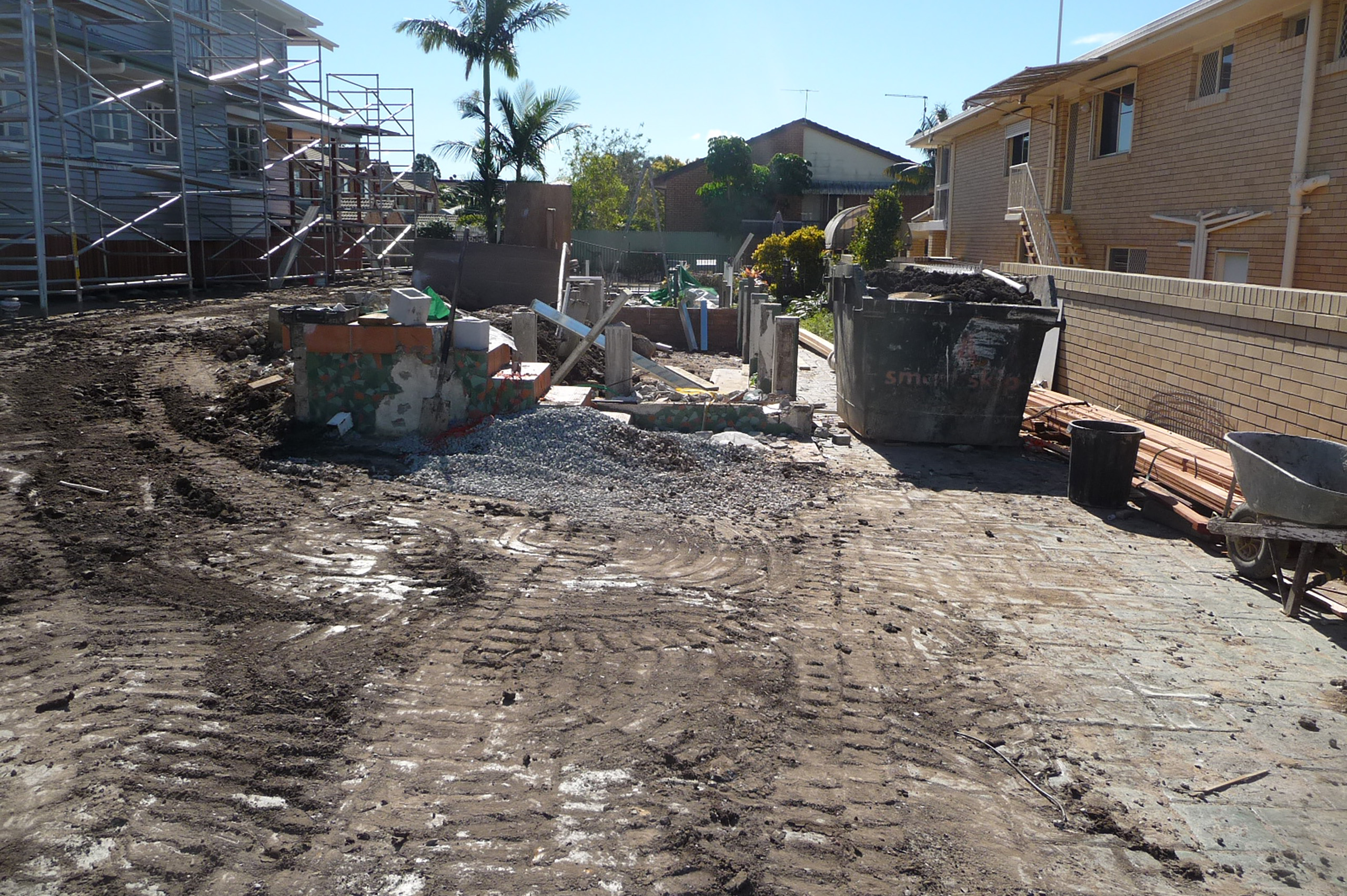 Demolition site at Carina Heights showing exposed earth, construction debris, and a skip bin between neighbouring brick and timber homes. Site clearance reflects the early stage of a project where demolition approval in Brisbane was successfully obtained.