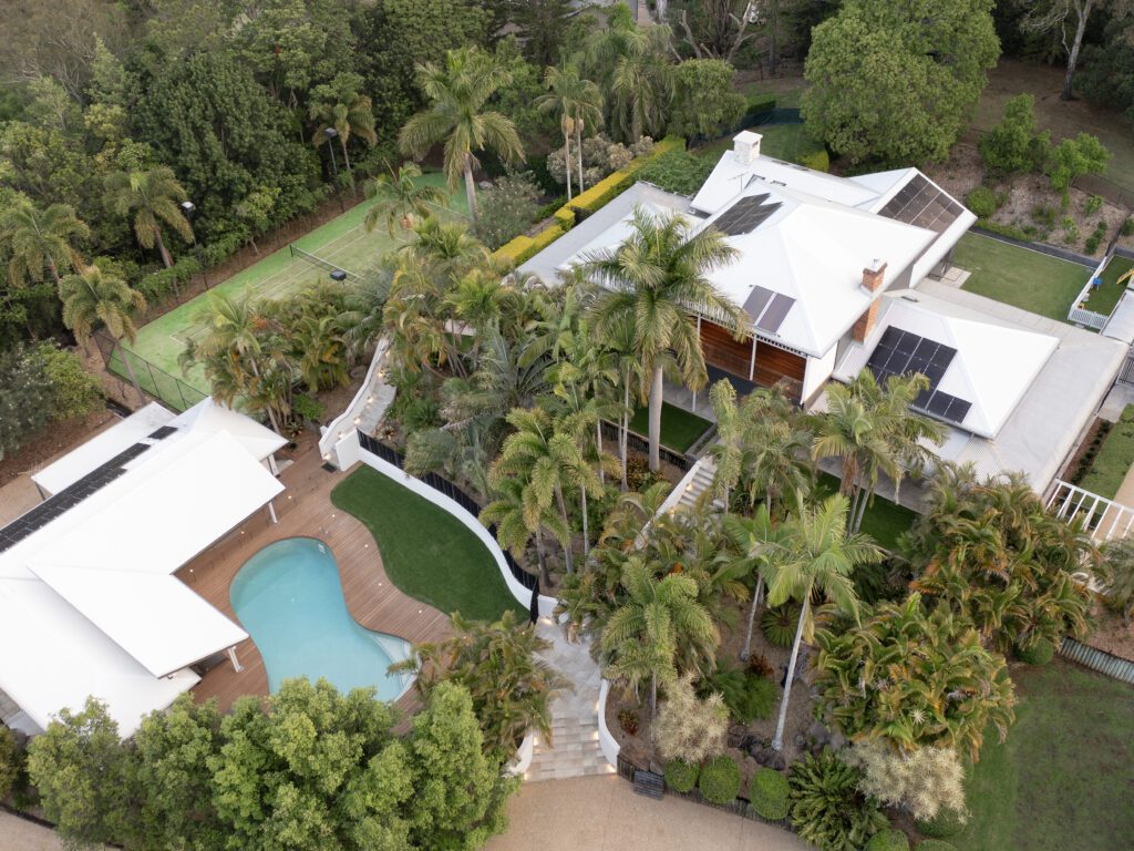 Aerial view of a luxury Brisbane home with pool, landscaped gardens, and solar panels, showing the lifestyle benefits of architect-designed living.